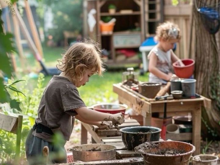 To børn der rører mudder i mudderkøkkenet