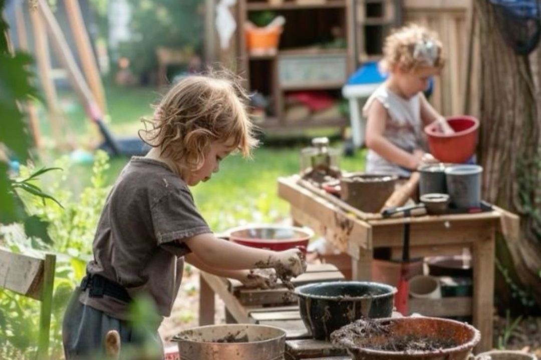 To børn der rører mudder i mudderkøkkenet
